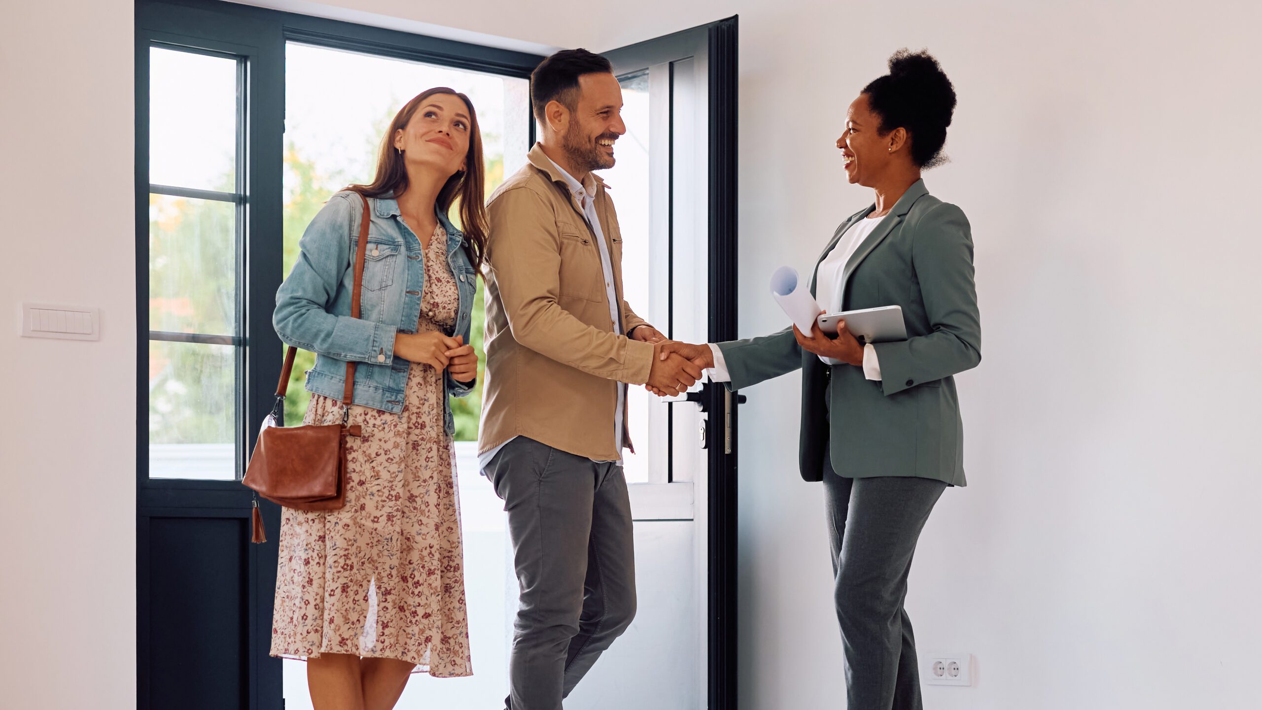 Happy couple meeting with real estate agent while buying a new house.